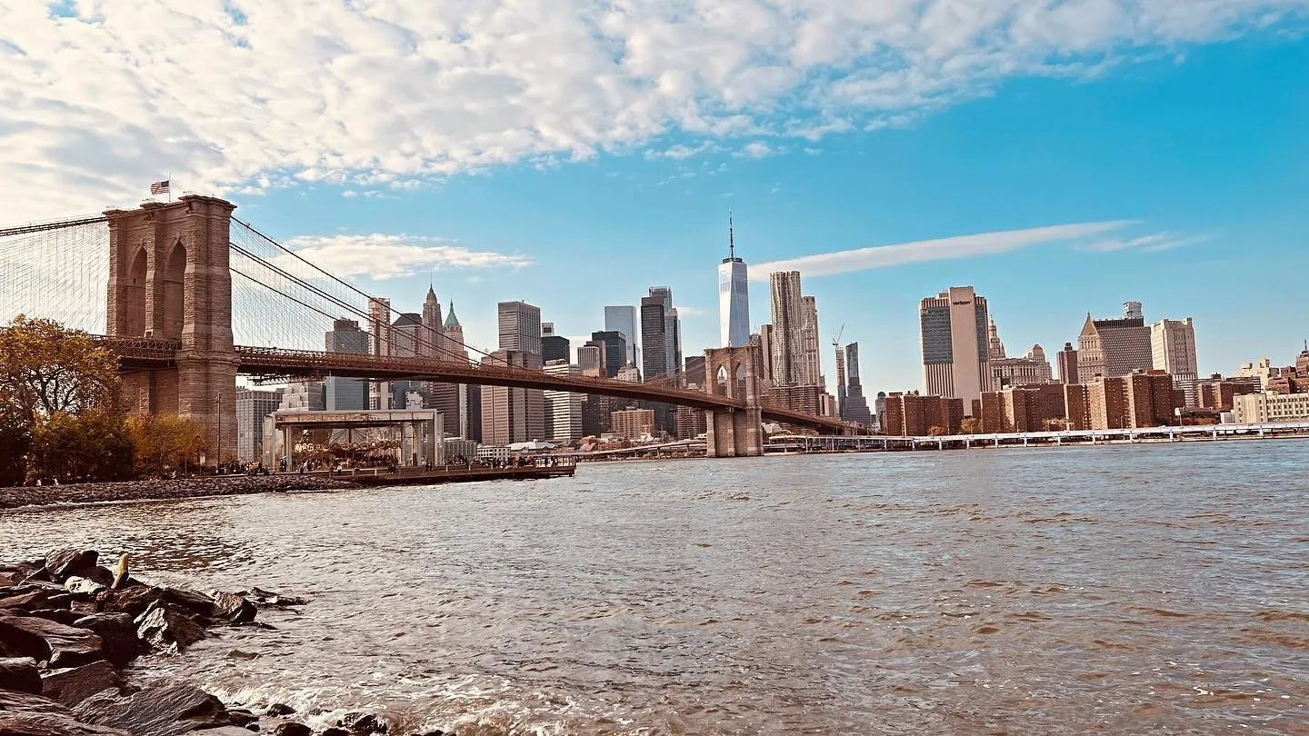 The Brooklyn Bridge and the Lower Manhattan skyline seen from the Brooklyn shoreline on a clear autumn afternoon