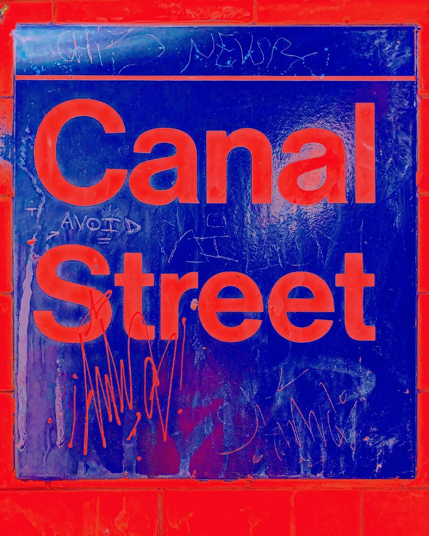 The tiled Canal Street subway sign, red letters on deep blue, scratched over with marker tags