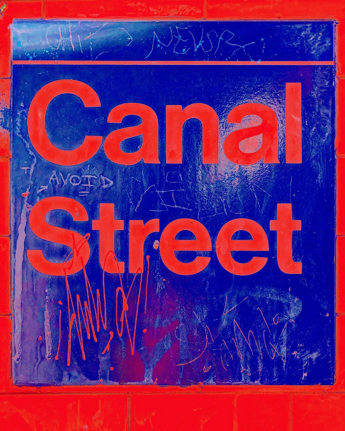 The tiled Canal Street subway sign, red letters on deep blue, scratched over with marker tags