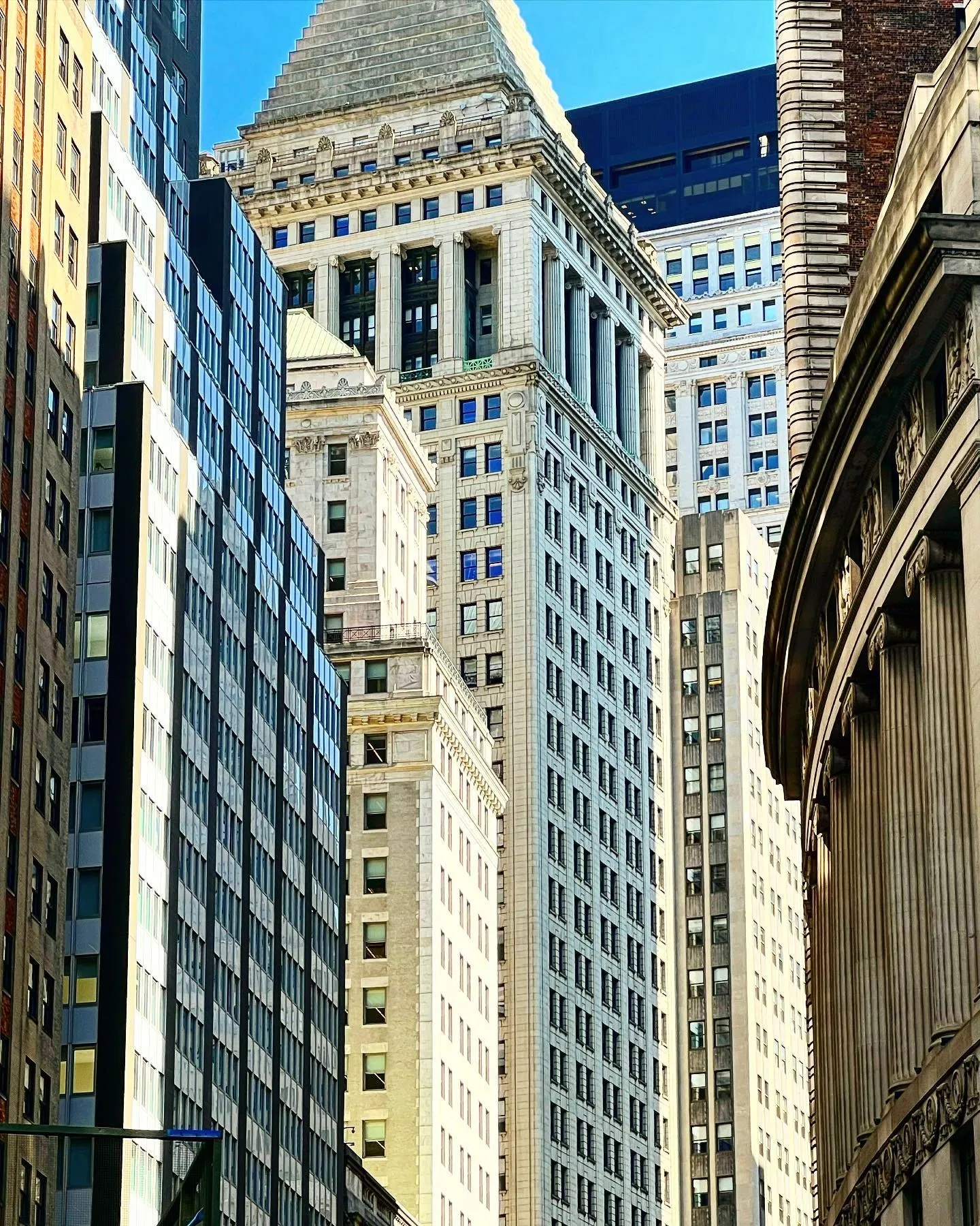 Downtown Manhattan office towers stacked against each other, looking up from the street on a bright day