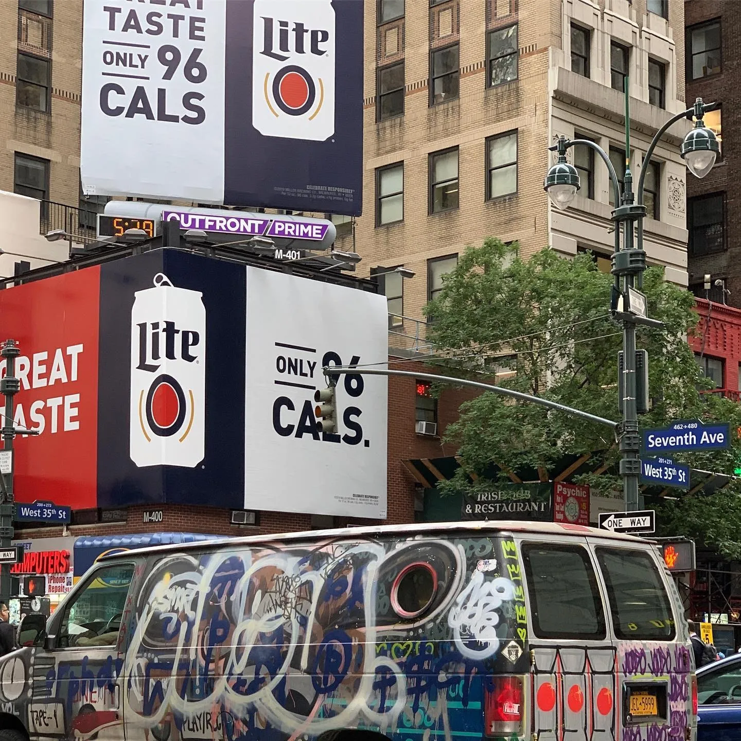 A van covered in graffiti tags parked under billboards at Seventh Avenue and West 35th Street