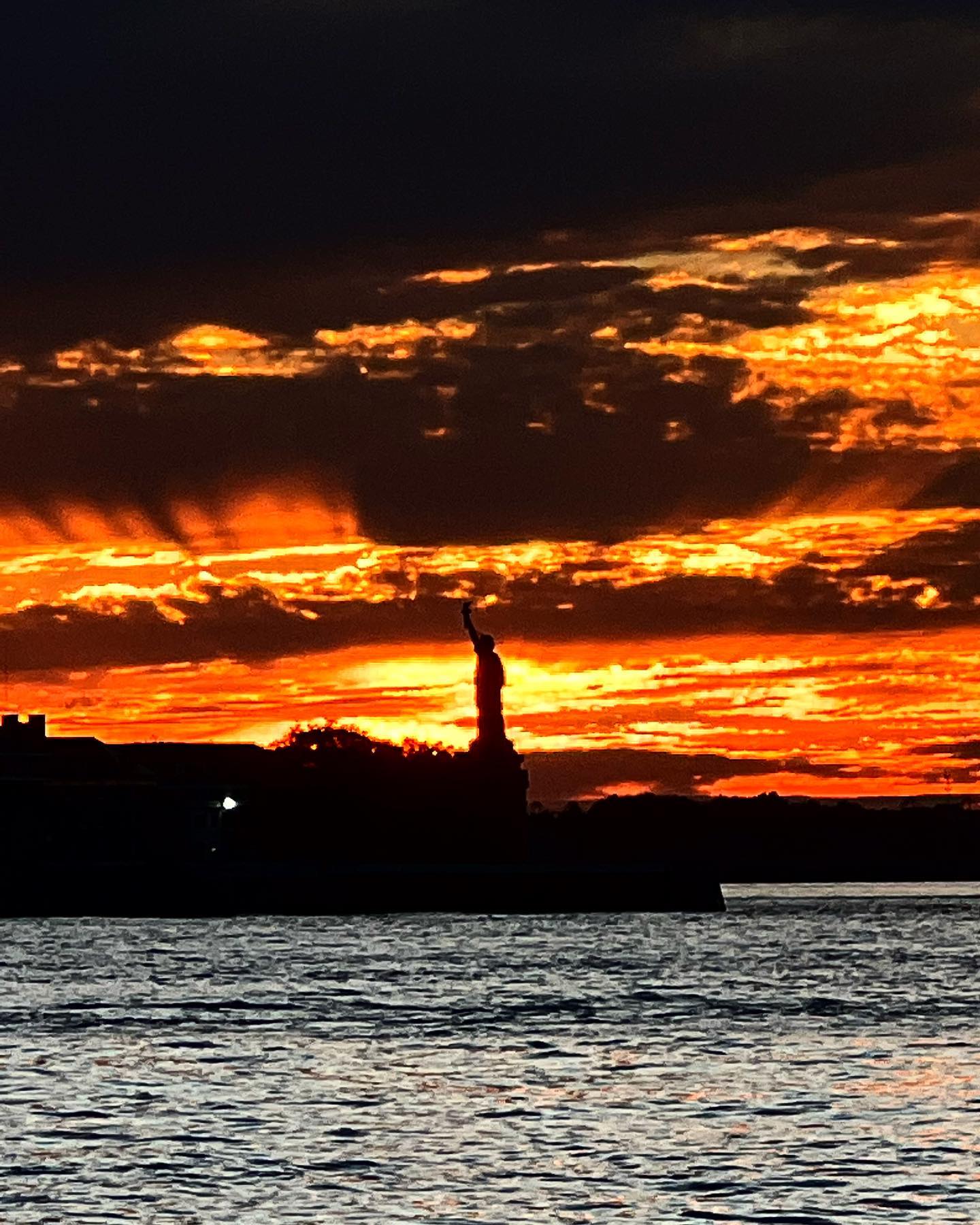 The Statue of Liberty silhouetted against an orange sunset