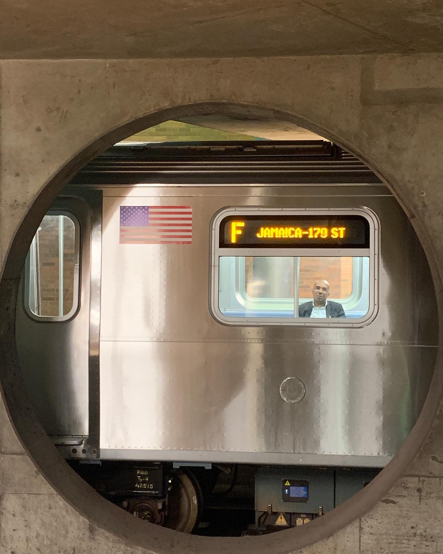 A New York City subway train framed by a circular station opening