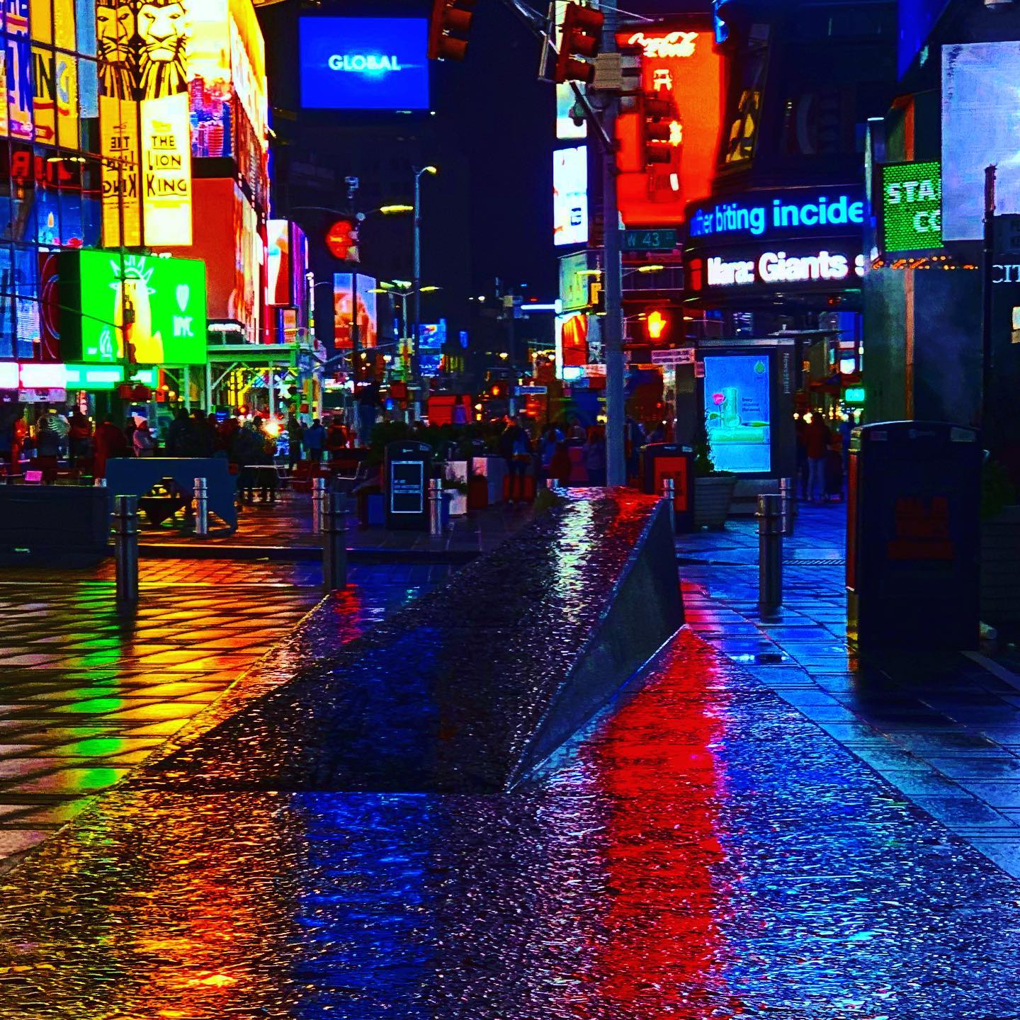 Times Square lights reflecting on wet pavement at night