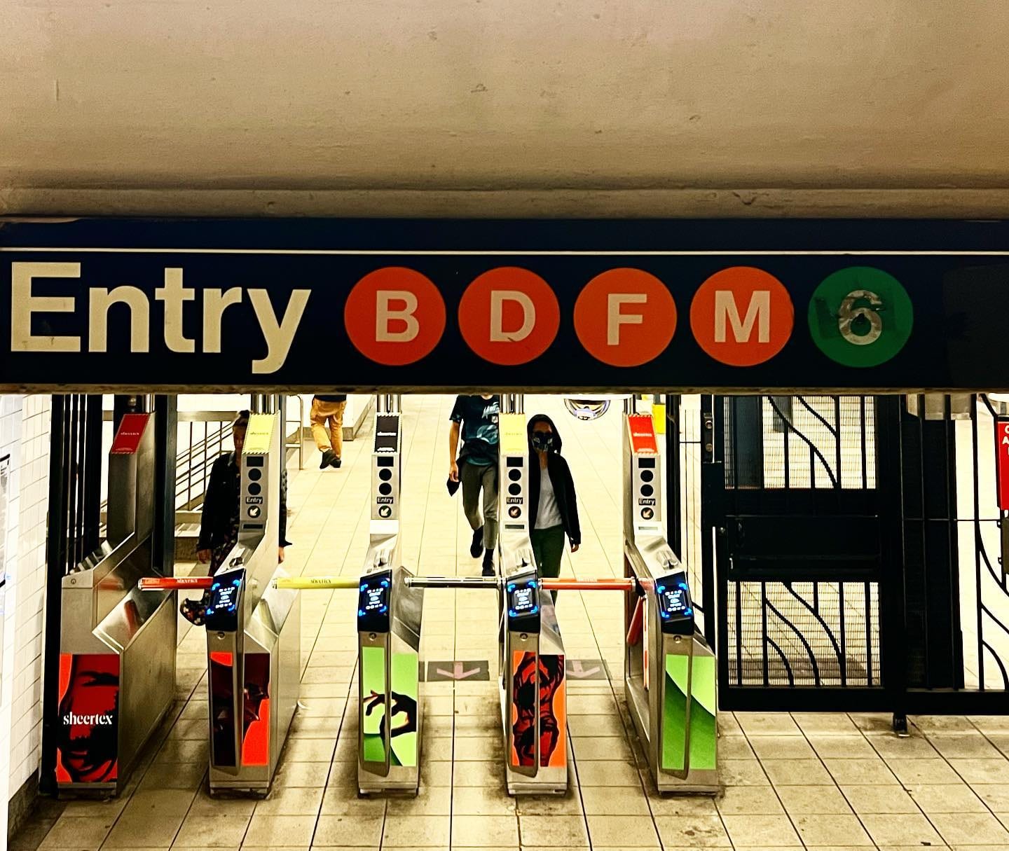 Subway turnstiles under an entry sign for the B, D, F and M trains.