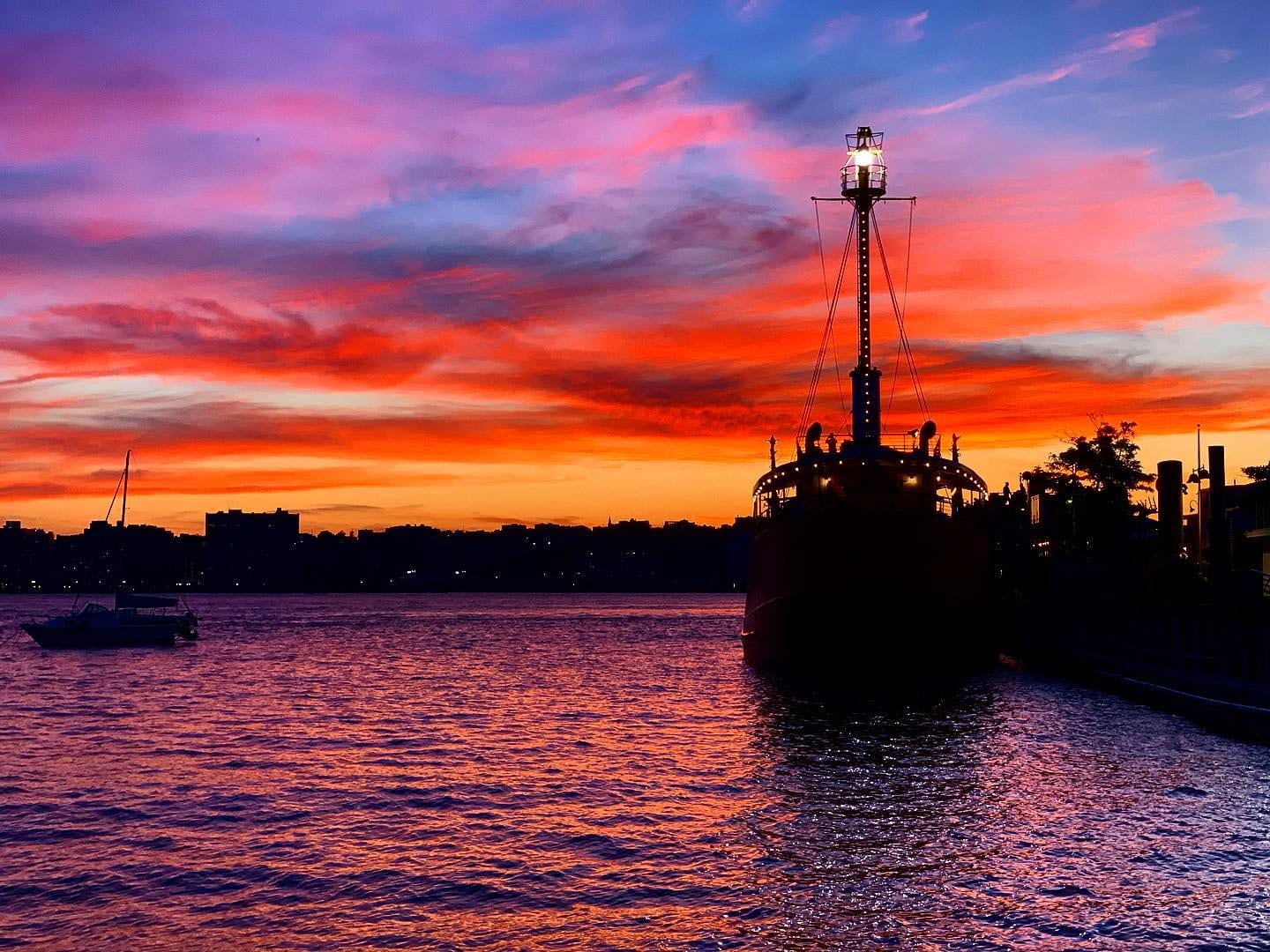 A boat silhouetted on the harbor under a pink and orange sunset.