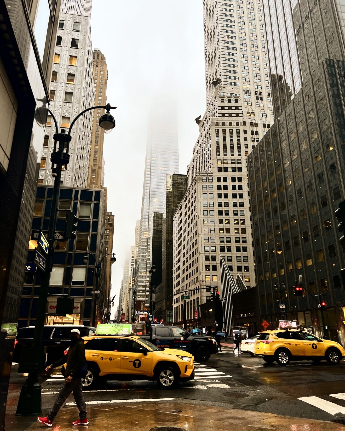 Yellow cabs waiting at a light on a Midtown avenue, office towers closing in on both sides.